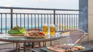 a table with two plates of food and two glasses of beer at Sokcho Jaja Ocean View Pension in Sokcho
