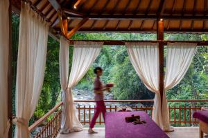 a woman standing on a balcony looking out of a window at Adiwana Svarga Loka - A Retreat Resort in Ubud