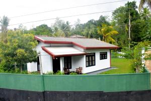 a small white house behind a green fence at Chenudi Villa Ahangama in Ahangama