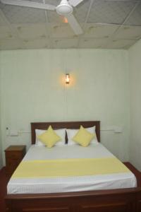 a bedroom with a bed with yellow pillows and a ceiling at Chenudi Villa Ahangama in Ahangama