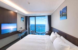 a hotel room with a bed and a television at Ramada by Wyndham Gangwon Sokcho in Sokcho