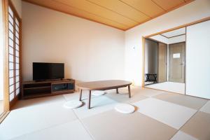 a living room with a table and a tv at Suma Beach House Ref in Takatorichō