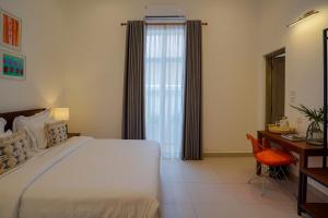 a bedroom with a large bed with a desk and a window at Eklektik in Colombo