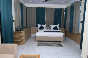 a bedroom with a bed and a desk and curtains at Prakriti Hill Resort in Nandaprayāg +52 photos