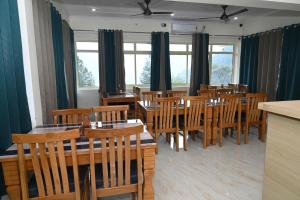 a restaurant with wooden tables and chairs and windows at Prakriti Hill Resort in Nandaprayāg