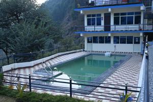 a swimming pool in front of a house at Prakriti Hill Resort in Nandaprayāg