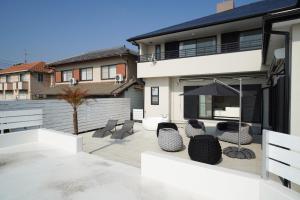 a patio with chairs and an umbrella in a house at Suma Beach House Ref in Takatorichō