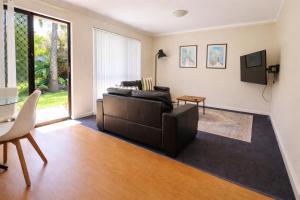 a living room with a couch and a tv at Beachside Garden Apt Beach Scarborough with Parking in Perth
