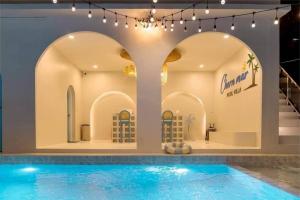 a swimming pool in a building with arches at Chern Mar Pool Villa Cha-am in Cha Am