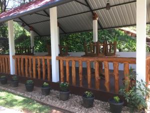 a porch with a wooden fence and potted plants at Mimi's Cottage in Udawalawe