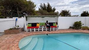 a woman sitting on a bench next to a pool at Marina Dreams Studio Apartment in Marina Da Gama