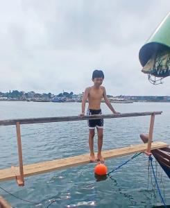 a young boy standing on a dock in the water at Warram mobile in Puerto Princesa City