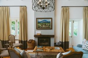 a living room with a fireplace and a chandelier at Auberge Clermont in Franschhoek
