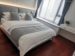 a bed with white sheets and pillows in a bedroom at SeaHear Premier in Rizhao