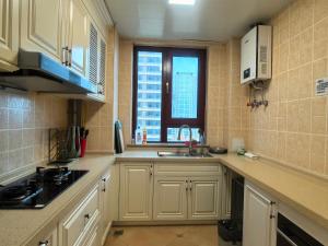 a kitchen with white cabinets and a sink and a window at SeaHear Premier in Rizhao