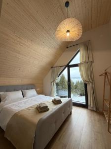 a bedroom with a large bed and a large window at Cabana Nord Side in Muntele Cacovei