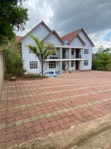 a white house with a palm tree and a brick driveway at Tulivu Nyumba in Arusha