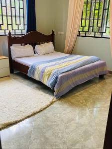 a bed sitting in a room with windows at Tulivu Nyumba in Arusha