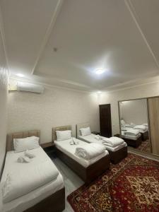 a room with three beds and a mirror at Abu Zarr Terrace in Bukhara