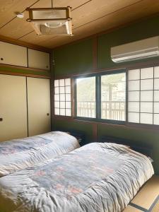 a bedroom with a bed and two windows at tsudoi in Tanabe