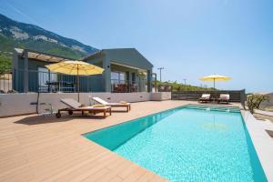 a swimming pool with benches and umbrellas next to a house at Villa Katoikia Dio by Villa Plus in Simotáta