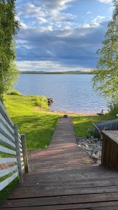a wooden pathway leading to a lake with a bench at Genuine Beach House and Sauna in Pello