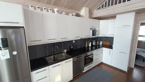 a kitchen with white cabinets and a stainless steel refrigerator at Genuine Beach House and Sauna in Pello