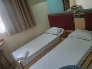two beds in a small room with a window at Hotel metrosul Ltda in São Paulo