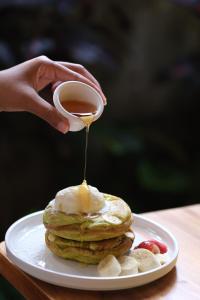 a person drizzling peanut butter on a stack of pancakes at Lembu Putih House in Tegalalang
