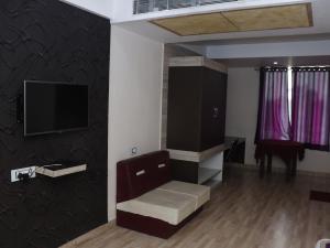a living room with a chair and a flat screen tv at Heritage Tezpur in Tezpur