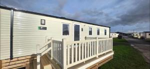 a mobile home with a porch and a fence at T&K's Caravan in Morecambe