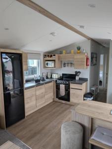 a kitchen with wooden cabinets and a black refrigerator at T&K's Caravan in Morecambe
