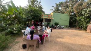 a group of people sitting around a table at Hampi Banana Farm House in Hospet
