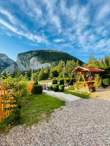 a picnic shelter in a garden with a mountain in the background at Vila Adela in Lacu Rosu