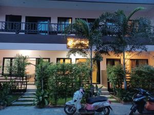 two scooters parked outside of a building with palm trees at Myhomevillage in Ko Tao