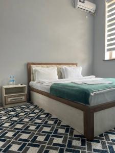 a bedroom with a large bed with a green blanket at Grand mountain hotel in Baysun
