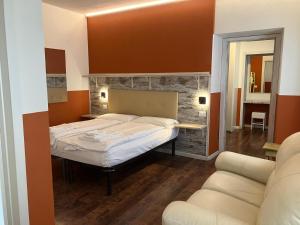 a bedroom with a large bed and a couch at HOTEL GARNI BARANCIO - Auronzo center in Auronzo di Cadore