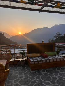 a bed on a balcony with the sunset in the background at Namaste Hostel Rishikesh in Rishīkesh