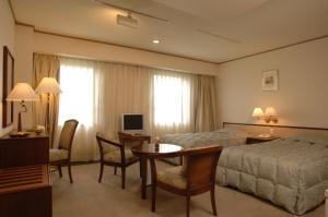 中津市にあるグランプラザ中津ホテルのベッド、デスク、テーブルが備わる客室です。