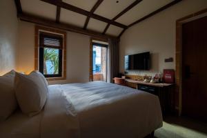 a bedroom with a large white bed and a television at Olwen Boutique Hotel in Danang