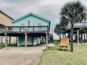 a blue house with a deck and a wooden chair at Bailey Beach House Beach Views in Freeport