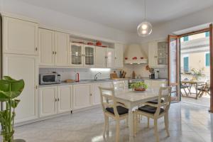 a kitchen with white cabinets and a table with chairs at A Casa di Nonna Anna in Porto Azzurro