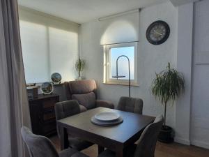 a living room with a table and chairs and a clock at Chalet Laguna Rosa in Torrevieja