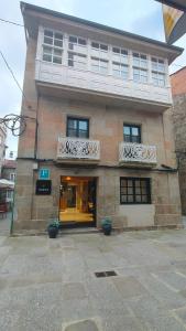 a large brick building with two balconies on it at Hostal HCELENIS in Caldas de Reis +29 photos