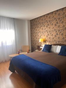 a bedroom with a large bed with a blue blanket at Hotel Villa de Biar in Biar