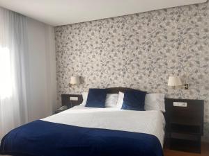 a bedroom with a bed with blue and white sheets at Hotel Villa de Biar in Biar