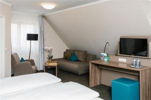 a living room with a couch and a flat screen tv at Hotel & Tagungszentrum Blaubeuren - Hessenhöfe in Blaubeuren