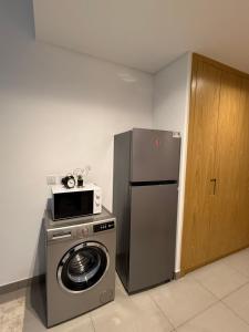 a kitchen with a washing machine and a refrigerator at Modern studio Al mamsha by Alef in Sharjah
