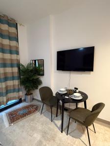 a living room with a table and chairs and a tv at Modern studio Al mamsha by Alef in Sharjah