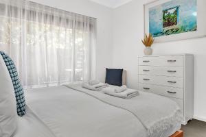 a white bedroom with a bed and a dresser at Secure Suite in Gated Complex, Courtyard, 5 Min CBD in Rose Park